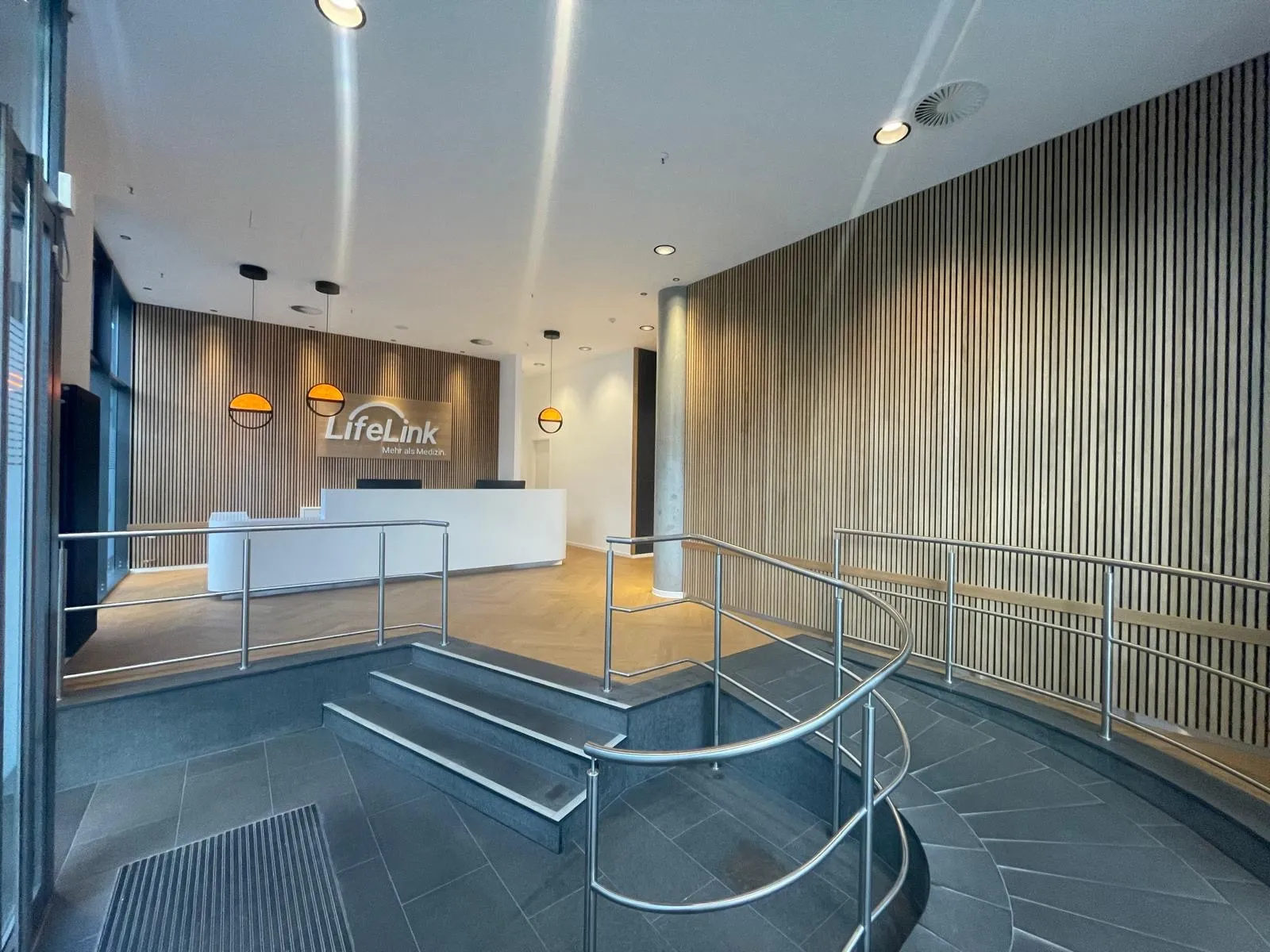Foyer mit großformatigen Bodenplatten, Stufenbelag und Übergang zum Parkett